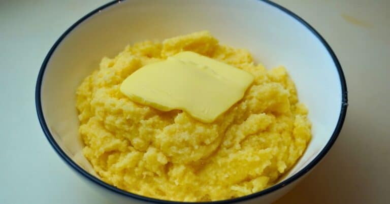 Cooked instant polenta with butter on top in a bowl on a table